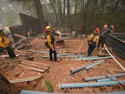 Jon Cappleman en pleine conversation avec des pompiers venus inspecter les environs de sa propriété, à Twain, en Californie, le 26 juillet 2021 - Robyn Beck [AFP]
