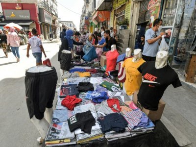 Une femme achète des vêtements à un marchand au souk de Bab el-Fellah, à Tunis, le 28 juillet 2021 - FETHI BELAID [AFP]