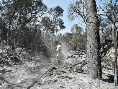 Un pompier s'active dans une zone brûlée d'un Club Méditerranée abandonné à Lambiri, à l'est de Patras (Grèce), le 1er août 2021 - LOUISA GOULIAMAKI [AFP]