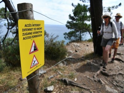Des randonneurs à proximité d'une une pancarte indiquant l'interdiction d'accès à la plage de l'Ile Vierge à Crozon dans le Finistère, le 29 juillet 2021 - Fred TANNEAU [AFP]
