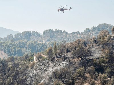 Un hélicoptère Sikorsky S-64 Skycrane survole une propriété ravagée par un incendie dans le village de Ziria, près de Patras, le 1er août 2021 - Louisa GOULIAMAKI [AFP]