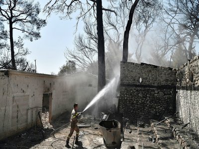 Un pompier grec lutte contre le feu sur un site abandonné du Club Méditerranée à Lambiri, près de Patras, le 1er août 2021 - LOUISA GOULIAMAKI [AFP]
