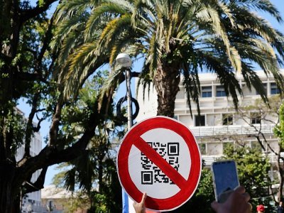 Un manifestant brandit un panneau imitant un QR code lors d'une manifestation contre le pass sanitaire à Saint-Denis de la Réunion le 31 juillet 2021 - Richard BOUHET [AFP]