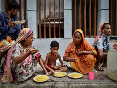 Des personnes apauvries par la crise du coronavirus mangent un repas offert par l'association Mehmankhana, le 26 juillet 2021 à Dacca - Munir Uz zaman [AFP]