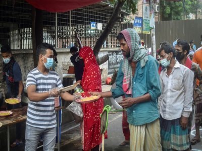 Un bénévole de l'association Mehmankhana distribue des repas à des personnes sans ressources affectées par la crise sanitaire,  le 26 juillet 2021 à Dacca - Munir Uz zaman [AFP]