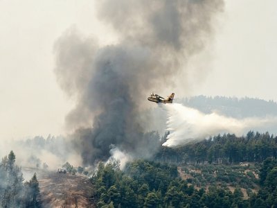 Un avion bombardier d'eau survole le village de Kourkouli (nord de Eubée) pour lutter contre les incendies, le 5 août 2021 - Louisa GOULIAMAKI [AFP]