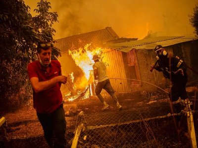 Des pompiers aidés d'habitants tentent d'éteindre le feu dans un village sur l'île grecque d'Eubée, le 10 août 2021 - ANGELOS TZORTZINIS [AFP]