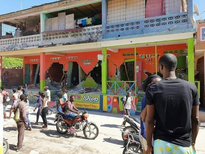 Des passants près d'une maison effrondrée dans une rue de la ville de Jérémie, près de l'épicentre du séisme au sud-ouest de la péninsule d'Haïti, le 14 août 2021 - Tamas JEAN PIERRE [AFP]