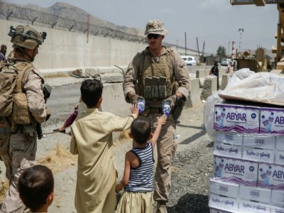 Une photographie publiée par l'armée américaine montre un militaire américain donnant de l'eau à des enfants pendant les opérations d'évacuations à l'aéroport international de Kaboul le 20 août 2021 - Nicholas GUEVARA [US MARINE CORPS/AFP]