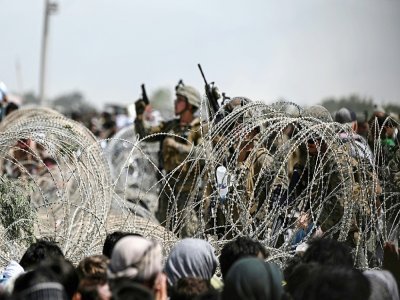 Un soldat américain tire en l'air devant une foule d'Afghans bloqués par des barbelés sur une route à proximité de la zone militaire de l'aéroport de Kaboul, le 20 août 2021 - Wakil KOHSAR [AFP]