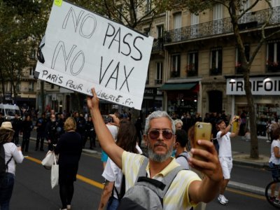 Un homme prend un selfie en tenant une pancarte lors d'une manifestation contre la vaccination obligatoire contre le Covid-19 pour certains travailleurs à Paris le 21 août 2021 - GEOFFROY VAN DER HASSELT [AFP]