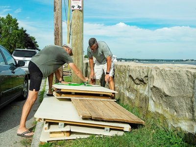 Deux membres d'une association de plage privée démontent une cahute de plage en prévision du passage de l'ouragan Henri, à New London (Connecticut), le 21 août 2021 - JOSEPH PREZIOSO [AFP]