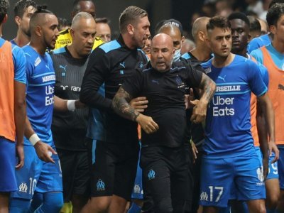 Le milieu de terrain de Marseille, Dimitri Payet (g) et l'attaquant turc Cengiz Under (d) tentent de calmer leur entraîneur, l'Argentin Jorge Sampaoli, après l'envahissement de supporters niçois lors du match de Ligue 1, le 22 août 2021 à l'Allianz R - Valery HACHE [AFP]