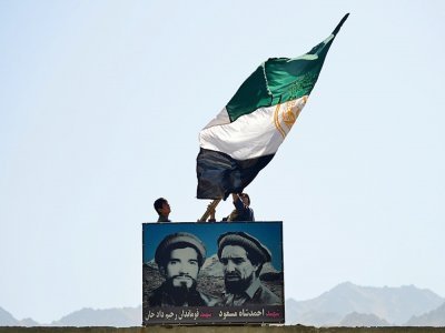 Des Afghans agitent un drapeau afghan au-dessus du portrait du commandant Massoud, dans la vallée du Panchir, le 23 août 2021 - Ahmad SAHEL ARMAN [AFP]
