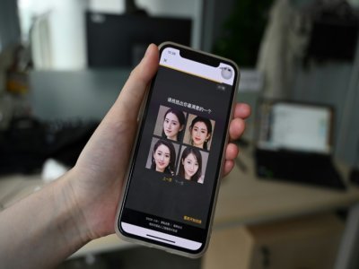 Un employé de XiaoIce montre sur son smartphone des photos de femmes virtuelles qui peuvent être choisies comme petites amies, le 5 juillet 2021 à Pékin - GREG BAKER [AFP]