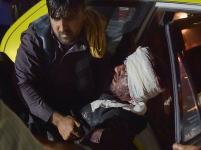 Un membre du personnel de l'hôpital de Kaboul sort d'une voiture un homme blessé dans les deux explosions qui ont frappé l'aéroport de la capitale, le 26 août 2021 - Wakil KOHSAR [AFP]