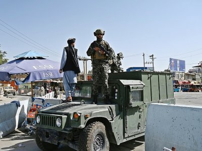 Des membres de l'unité "Badri 313", une composante des forces spéciales talibanes, dans des véhicules blindés Humvee devant l'entrée principale de l'aéroport de Kaboul, le 28 août 2021 - WAKIL KOHSAR [AFP]