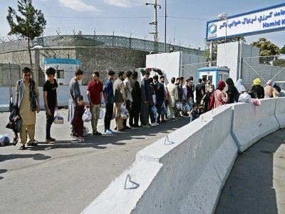 Des Afghans, espérant quitter le pays, font la queue devant l'entrée de l'aéroport de Kaboul, le 29 août 2021 - WAKIL KOHSAR [AFP]