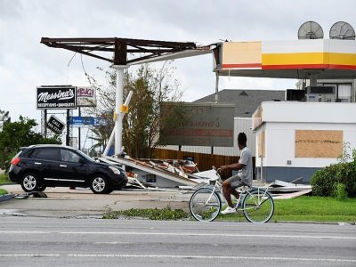 Un cycliste roule devant une station d'essence endomagée, à Kenner, en Louisiane, le 30 août 2021 - Patrick T. FALLON [AFP]