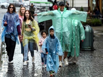 Des touristes des Pays du Golfe sous la pluie dans une rue de Lviv, le 17 août 2021 en Ukraine - Sergei GAPON [AFP]