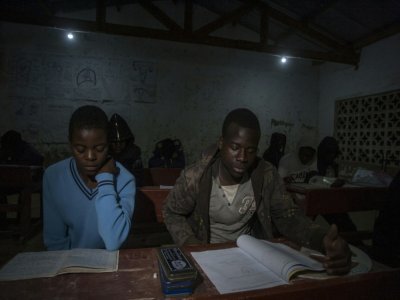 Des écoliers étudient à la lumière des ampoules dans le village de Yobe Nkosi  dans le Nord du Malawi, éclairés grâce à une petite centrale hydro-électrique artisanale - AMOS GUMULIRA [AFP]