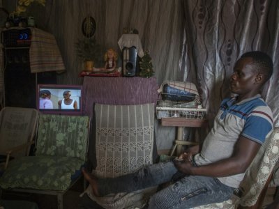 Un homme regarde le 23 août 2021 une télévision alimentée par une petite centrale hydro-électrique artisanale dans le village de Yobe Nkosi, dans le Nord du Malawi - AMOS GUMULIRA [AFP]
