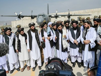 Le porte-parole des talibans Zabihullah Mujahid (au centre, avec le châle blanc) parle à la presse à l'aéroport de Kaboul, le 31 août 2021 - WAKIL KOHSAR [AFP]