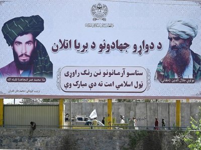 Des combattants talibans patrouillent à bord d'un véhicule devant un panneau portant des portraits du mollah Omar et Jalaluddin Haqqani, tous deux défunts, sur une route de Kaboul le 9 septembre 2021 - Aamir QURESHI [AFP]