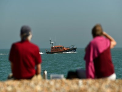 Un couple observe un bateau du secours en mer britannique sur la plage de Dungeness, le 7 septembre 2021, dans le sud-est de l'Angleterre - Ben STANSALL [AFP]