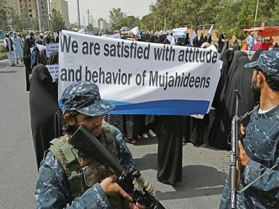 Des Afghanes en niqabs noirs défilent avec une pancarte "Nous sommes satisfaites de l'attitude et du comportement des moudjahidines (talibans)", devant l'Université Shaheed Rabbani, le 11 septembre 2021 à Kaboul - Aamir QURESHI [AFP]