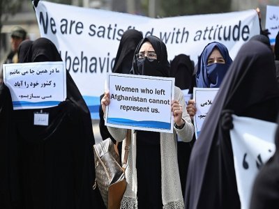 Une pancarte "Les femmes qui ont quitté l'Afghanistan ne peuvent pas nous représenter" brandie par une Afghane en niqab noir lors d'un rassemblement pro-talibans devant l'université Shaheed Rabbani, le 11 septembre 2021 à Kaboul - Aamir QURESHI [AFP]