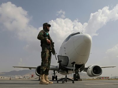 Un taliban armé monte la garde près d'un avion d'Ariana Afghan Airlines sur le tarmac de l'aéroport de Kaboul, le 12 septembre 2021 - Karim SAHIB [AFP]