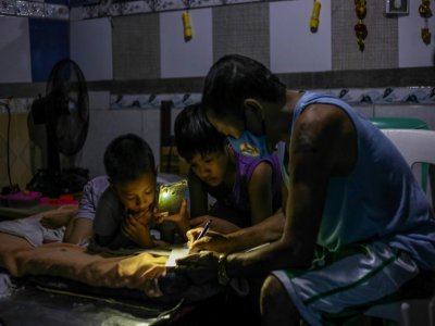 Petronilo Pacayra aide ses deux fils pour leurs devoirs scolaires, le 3 septembre 2021 à Manille, aux Philippines - Jam STA ROSA [AFP]