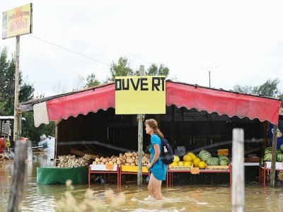 Une femme passe devant un étal de fruits et légumes dans une rue inondée à Codognan, dans le Gard, le 14 septembre 2021, à la suite de fortes pluies - Sylvain THOMAS [AFP]