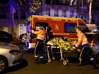 Des pompiers évacuent une personne blessée dans l'attaque du Bataclan, dans le nuit du 13 au 14 novembre 2015 à Paris - MIGUEL MEDINA [AFP/Archives]