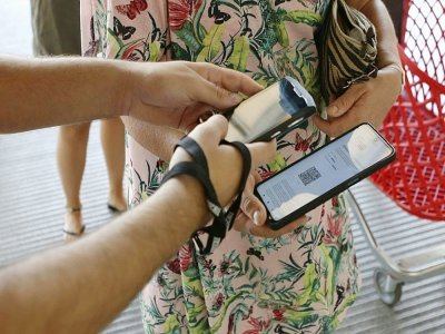 Une employée d'un centre commercial vérifie le pass sanitaire d'une cliente à Ajaccio, en Corse, le 16 août 2021 - Pascal POCHARD-CASABIANCA [AFP]