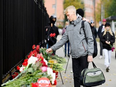 Un homme dépose des fleurs à l'entrée du campus de l'université de Perm (Russie), le 21 septembre 2021, au lendemain d'une tuerie qui a fait six morts - NATALIA KOLESNIKOVA [AFP]