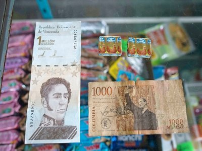 Billet d'un million de bolivars vénézuéliens (g) et son équivalent de 1000 pesos colombiens (d) dans une épicerie de Puerto Concha au Venezuela le 8 septembre 2021 - Federico PARRA [AFP]