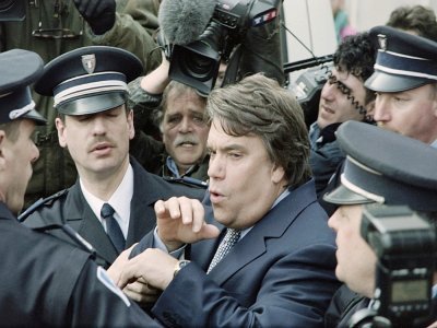 Escorté par des policiers, Bernard Tapie quitte un tribunal de Valenciennes, le 13 mars 1995 - Thomas COEX [AFP/Archives]