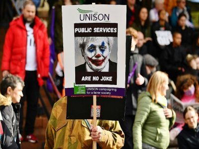 Un manifestant tient une pancarte caricaturant Boris Johnson en Joker lors d'une manifestation en marge de la Conférence annuelle des conservateurs à Manchester le 3 octobre 2021 - Ben STANSALL [AFP]