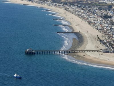 Le ponton de Huntington Beach, en Californie, et sa plage où des équipes de nettoyage s'affairent à dépolluer après une fuite de pétrole brut sur un oléoduc voisin, vus depuis un avion des gardes-côtes le 6 octobre 2021 - Patrick T. FALLON [AFP]