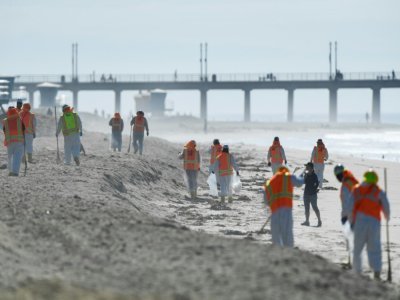 Des équipes de nettoyage dépolluent le sable près du ponton de Huntington Beach, en Californie, après une fuite sur un oléoduc voisin, le 5 octobre 2021 - Patrick T. FALLON [AFP]