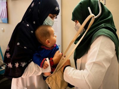 Une sage-femme et une diététicienne pèsent un bébé à la clinique de Tangi Saidan, le 6 octobre 2021 en Afghanistan - Elise BLANCHARD [AFP]