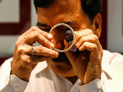 Un gérant de bijouterie examine à la loupe un bracelet en or, le 11 octobre 2021 à Bombay, en Inde - Punit PARANJPE [AFP]