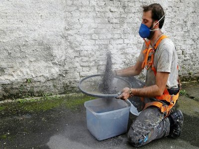 L'artiste brésilien Mundano tamisant la cendre d'Amazonie pour sa fresque à Sao Paulo le 13 octobre 2021 - Miguel SCHINCARIOL [AFP]