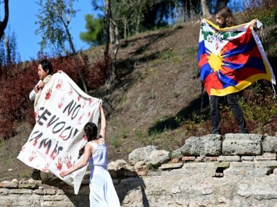 Manifestants avec un drapeau tibétain et une banderole lors de la cérémonie d'allumage de la flamme à Athènes le 18 octobre 2021 - ARIS MESSINIS [AFP]