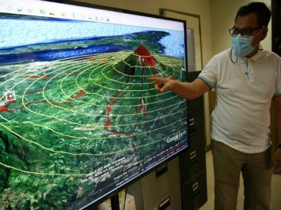 Eugene Escobar, chef de la division de la recherche du bureau de la sécurité publique et de la gestion des urgences d'Albay, montrant un écran vidéo montrant une simulation du volcan Mayon, dans son bureau de Legaspi, au sud de Manille, le 5 octobre - Ted ALJIBE [AFP]