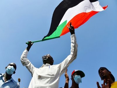Un manifestant soudanais anti-coup d'Etat brandit le drapeau national lors d'un rassemblement dans la ville d'Omdurman, jumelle de Khartoum, le 30 octobre 2021 - - [AFP]