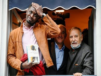 Le romancier sénégalais Mohamed Mbougar Sarr, au restaurant Drouant à Paris le 3 novembre 2021, avec à ses côtés Philippe Claudel et Tahar Ben Jelloun , membres du jury - Bertrand GUAY [AFP]