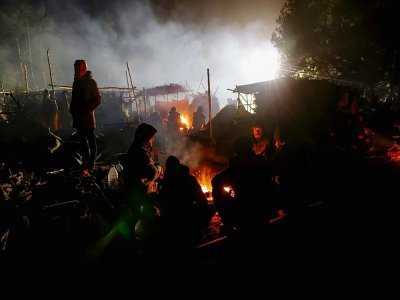 Des migrants se réchauffent près d'un feu le 14 novembre 2021 à la frontière entre le Bélarus et la Pologne - Oksana MANCHUK [BELTA/AFP]
